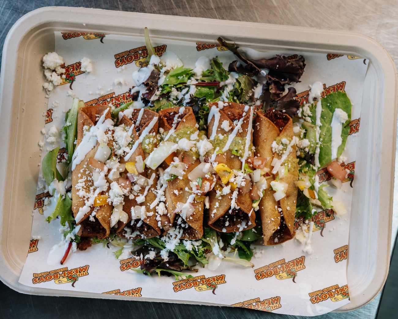 Crispy fried taquitos over greens with crema, salsa verde and cotija