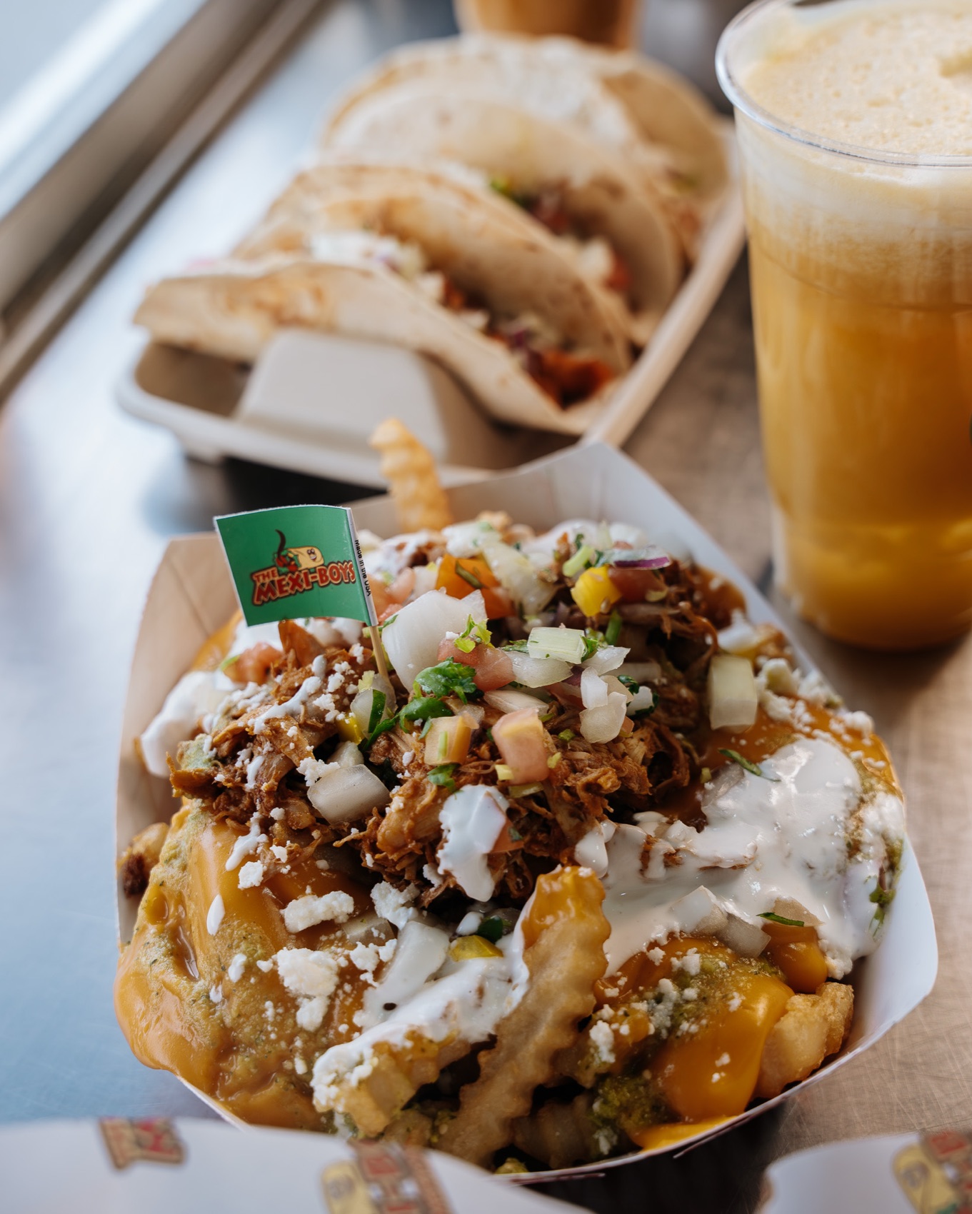Loaded Mexi-Fries piled with pulled protein, cheese, pico de gallo and crema in a Mexi-Boys tray