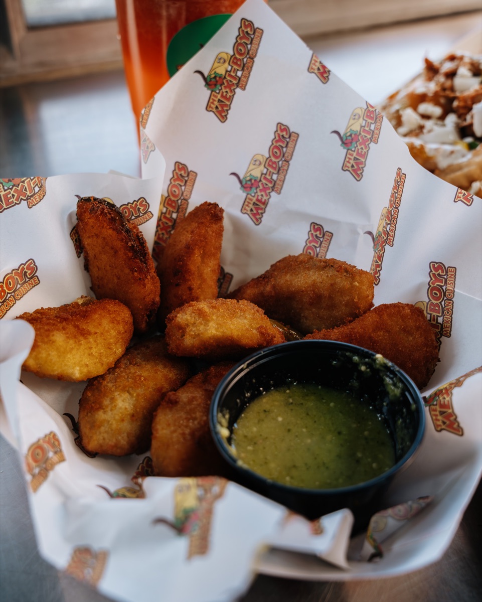 Basket of hand-breaded jalapeño poppers with salsa verde